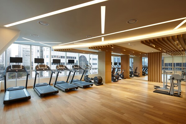 A modern gym with treadmills, stationary bikes, and weight machines.