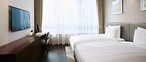 A hotel room with a bed, a desk, a chair, a TV, and a large window with curtains.