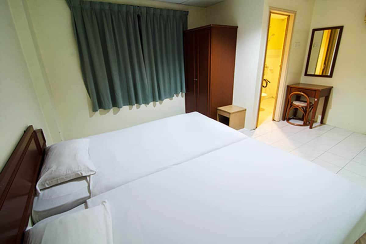 Una habitación de hotel con una cama grande, un armario, una mesita y una silla.
