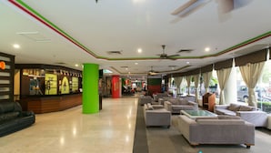 Eine Hotelhalle mit einer Rezeption, einer Sitzecke und großen Fenstern.