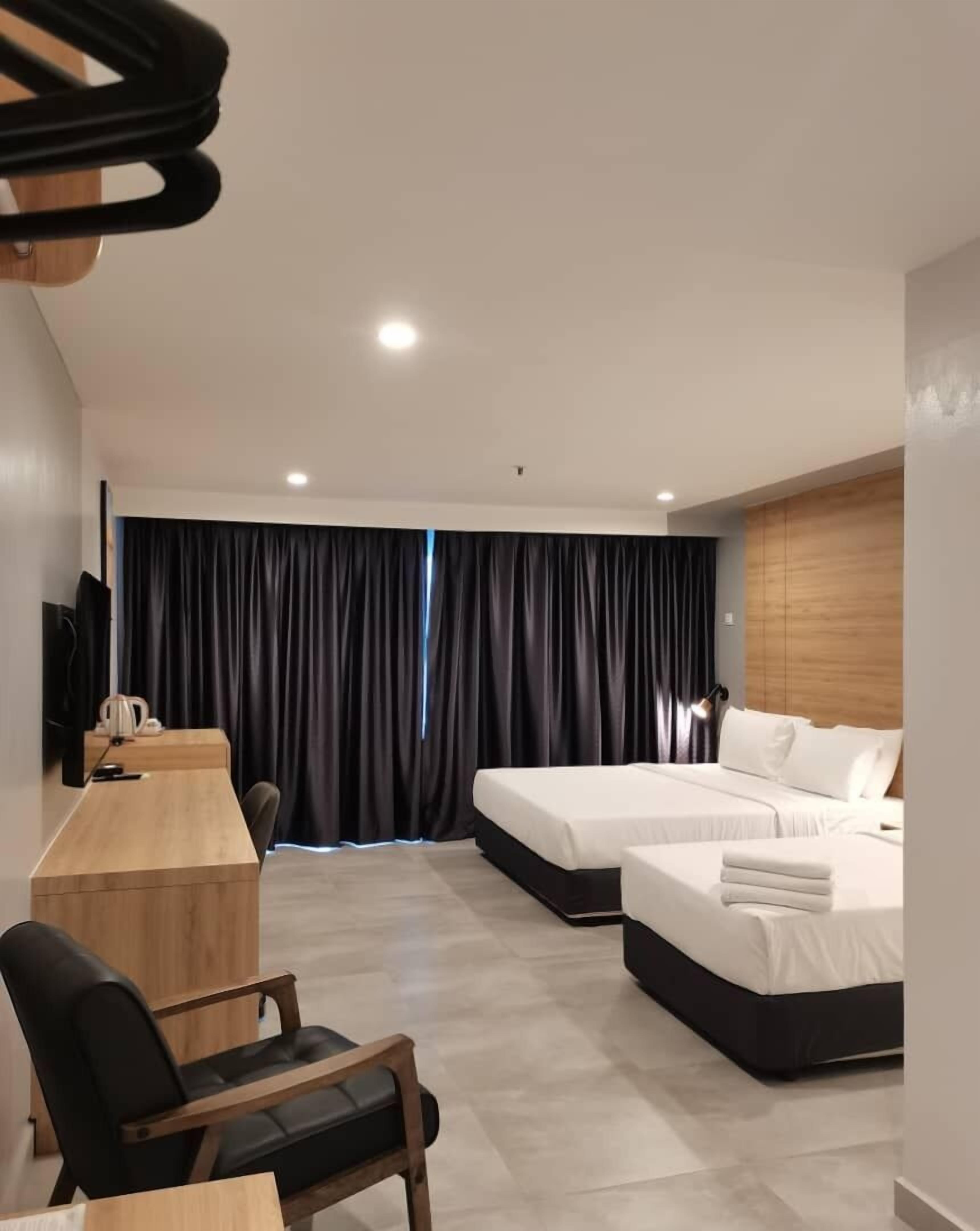 Una habitación de hotel con dos camas, un escritorio, una silla y un televisor.
