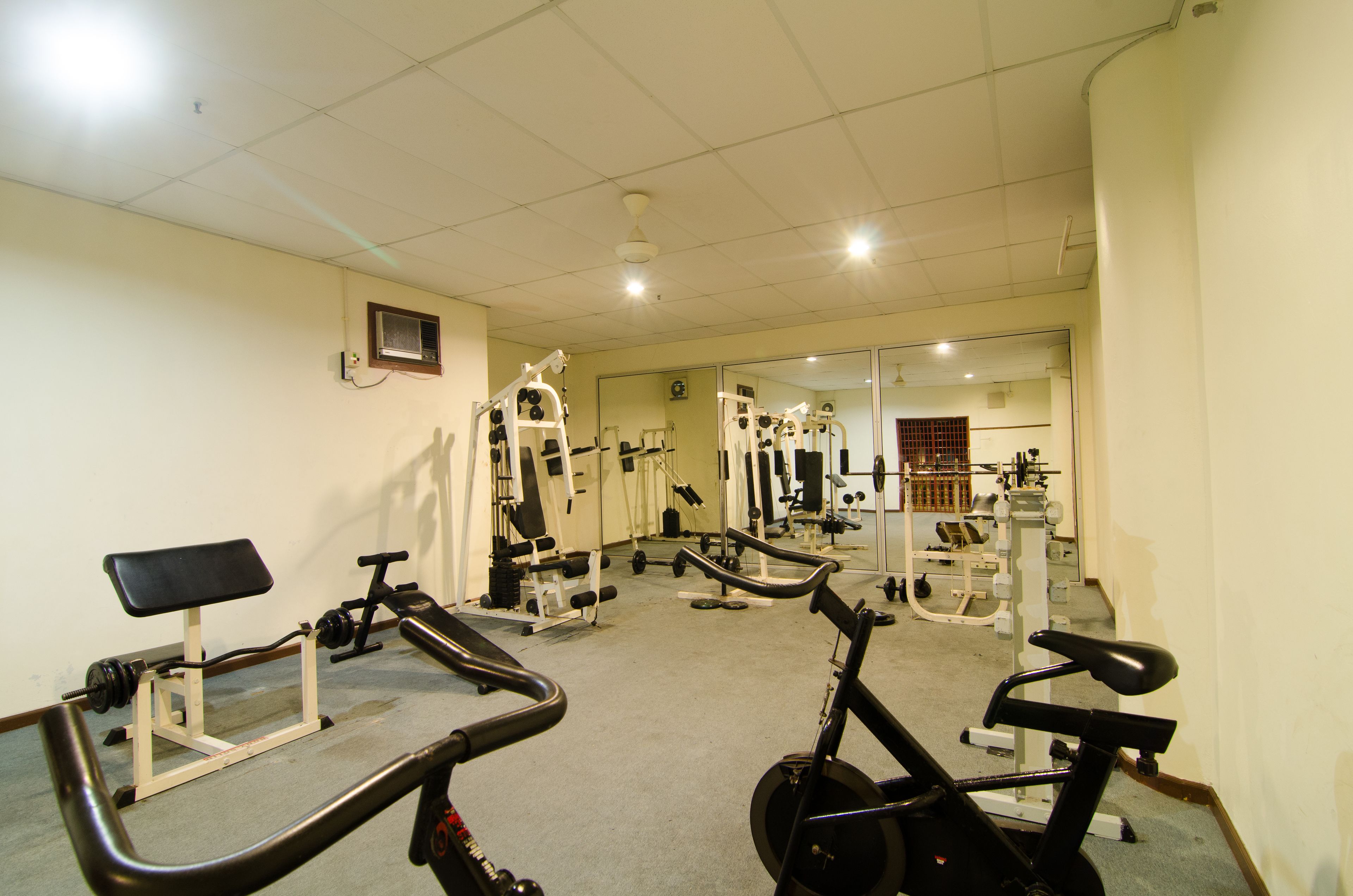 A gym with various exercise equipment, including treadmills, a bench, and weight machines.