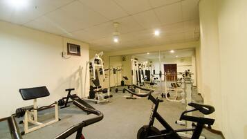 A gym with various exercise equipment, including treadmills, a bench, and weight machines.