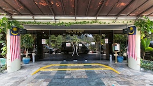 Der Eingang zum Coral Bay Resort mit einem überdachten Gang, der malaysischen und amerikanischen Flaggen und einem Schild, das ein Parkverbot anzeigt.