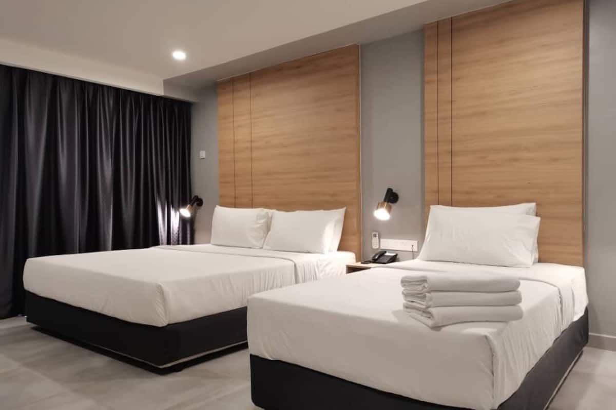 Una habitación de hotel moderna con dos camas, cortinas oscuras, cabeceros de madera, lámparas de noche y un espejo.