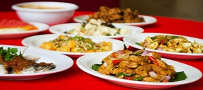 A table with various dishes, including fish and vegetables, on a red tablecloth. - Coral Bay Resort (Pangkor Island)
