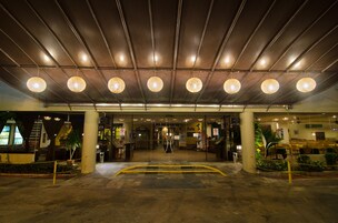 A hotel entrance with a covered walkway, potted plants, and a staircase leading to the entrance.