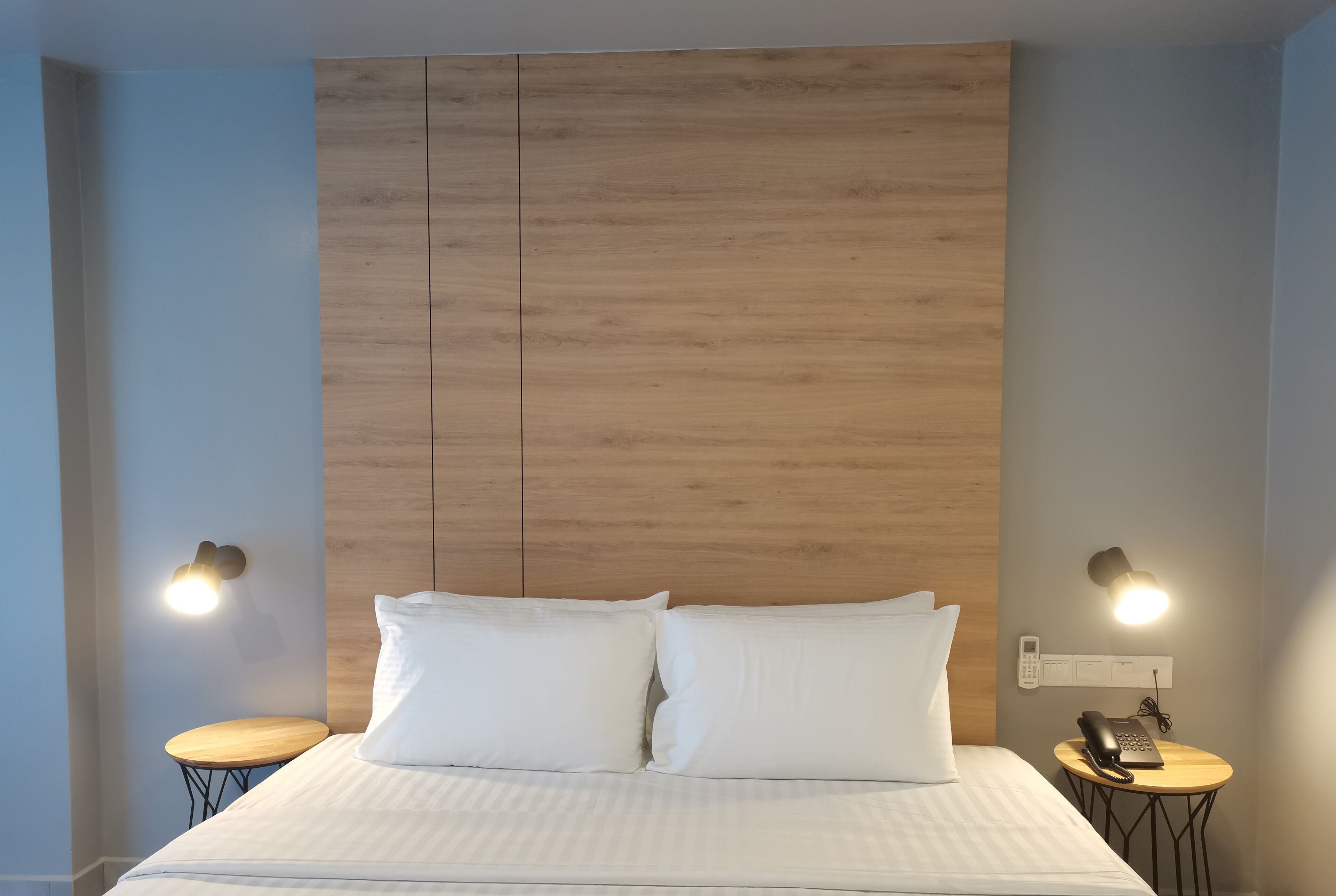 A neatly made bed with white linens, a wooden headboard, and two bedside tables with lamps.