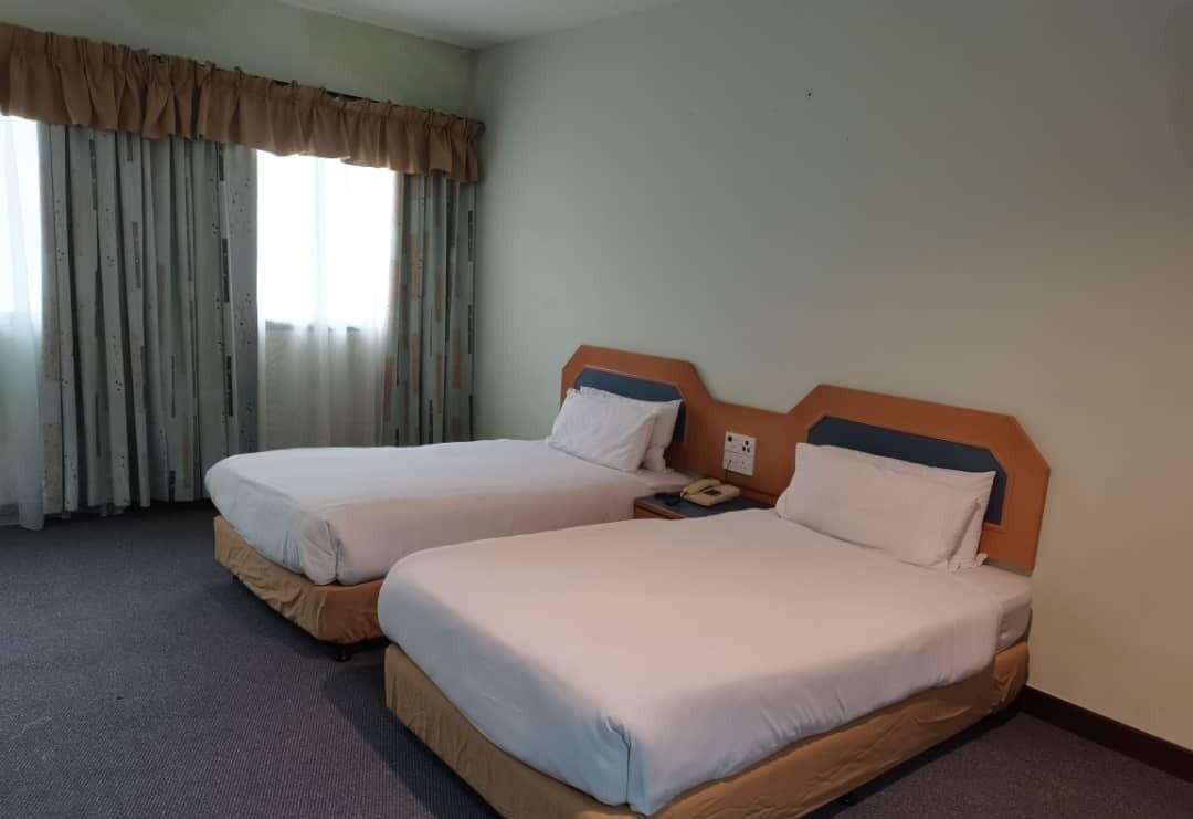 Una habitación de hotel con dos camas, una ventana con cortinas y un teléfono en la mesita de noche.