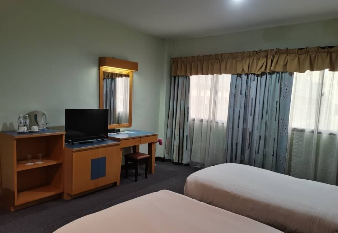A hotel room with a desk, television, and two beds.