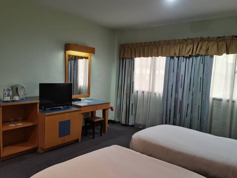 A hotel room with a desk, television, and two beds.