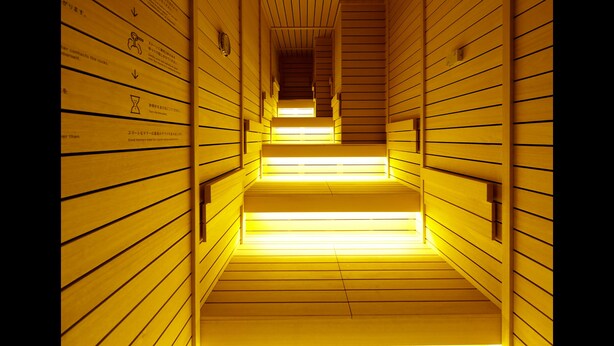 A wooden hallway with a sloped ceiling and illuminated steps. - ℃ (Do-C) Gotanda (Tokyo)