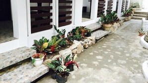 A covered walkway with potted plants and a stone pathway. - Ark Bayz Suites (Puerto Galera)