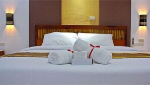 A neatly made bed with white linens, a wooden headboard, and two wall-mounted light fixtures. - Ark Bayz Suites (Puerto Galera)