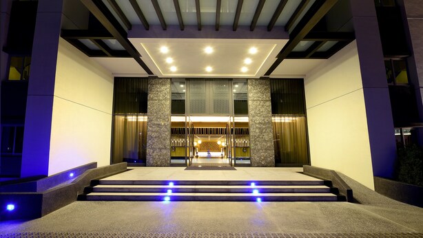 Een moderne gevel met een glazen deur, trappen en een plafond met inbouwverlichting.