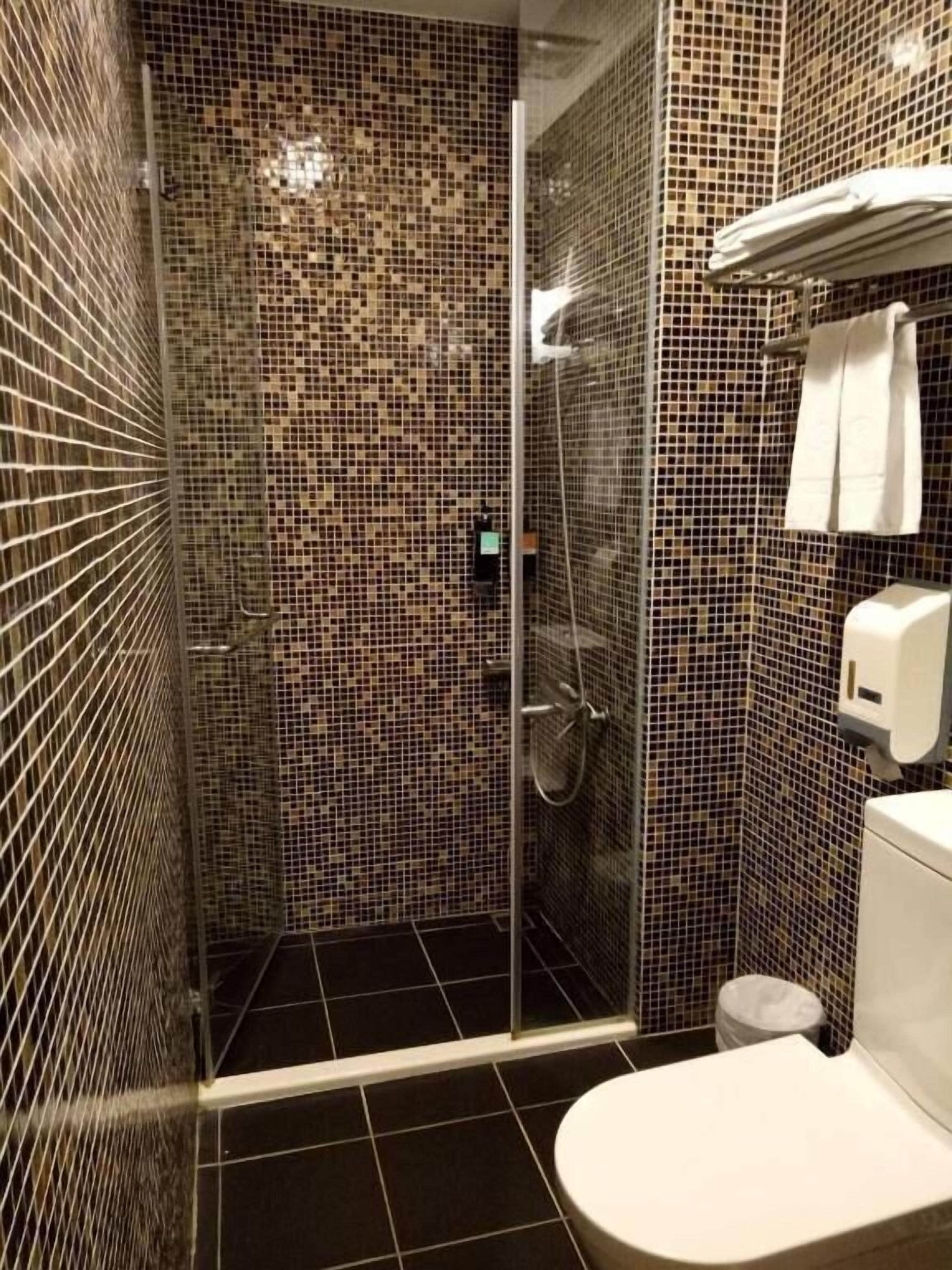A bathroom with a shower, toilet, and a hand dryer.