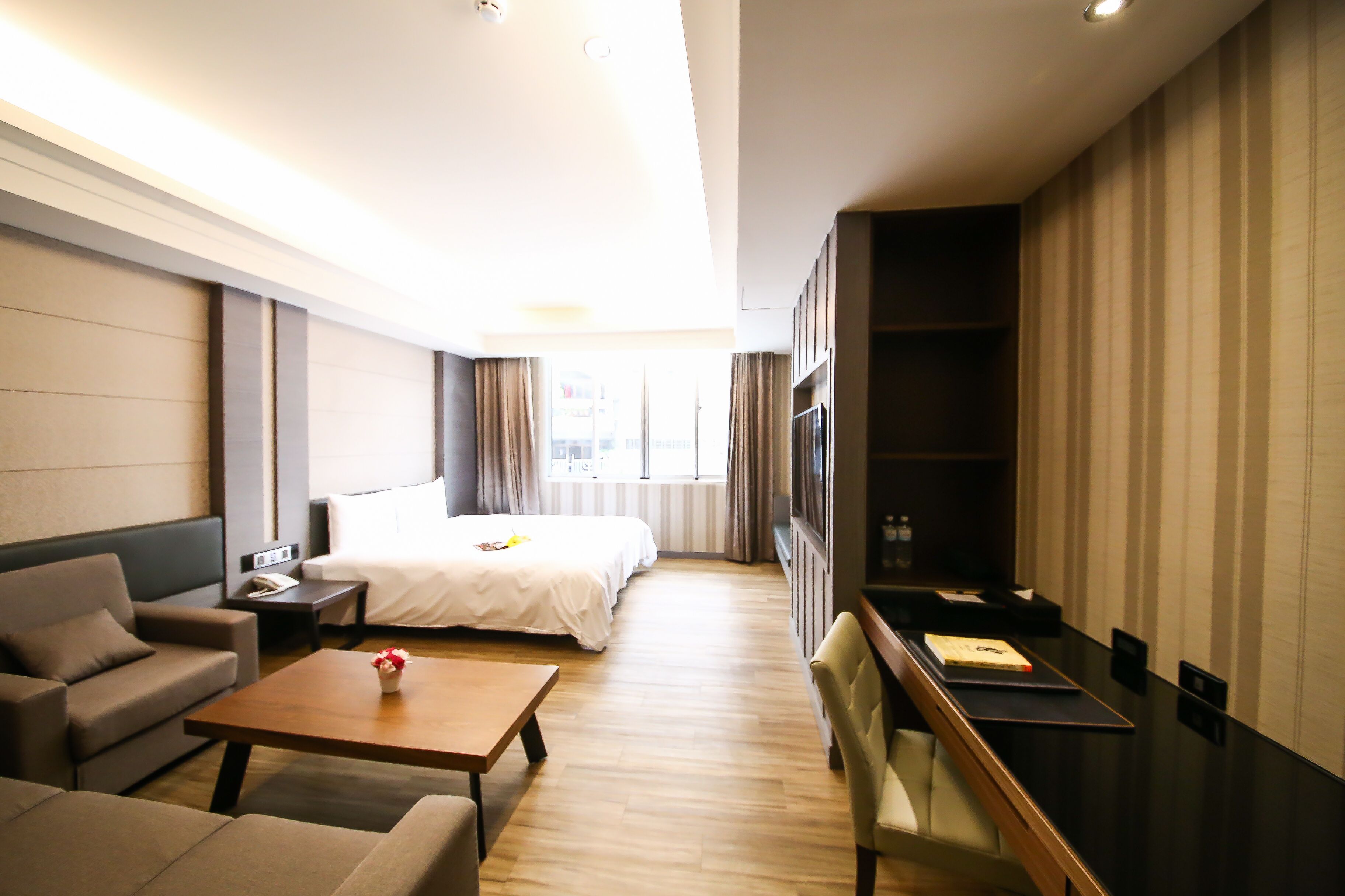 A modern hotel room with a bed, sofa, and a desk.
