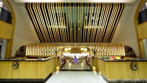 Een hotel lobby met een centrale trap, houten lambrisering en een kerstboom.