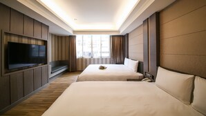 Een hotelkamer met twee bedden, een televisie en een raam met gordijnen.