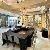 Una sala de conferencias moderna con una gran mesa rectangular, sillas y una araña.
