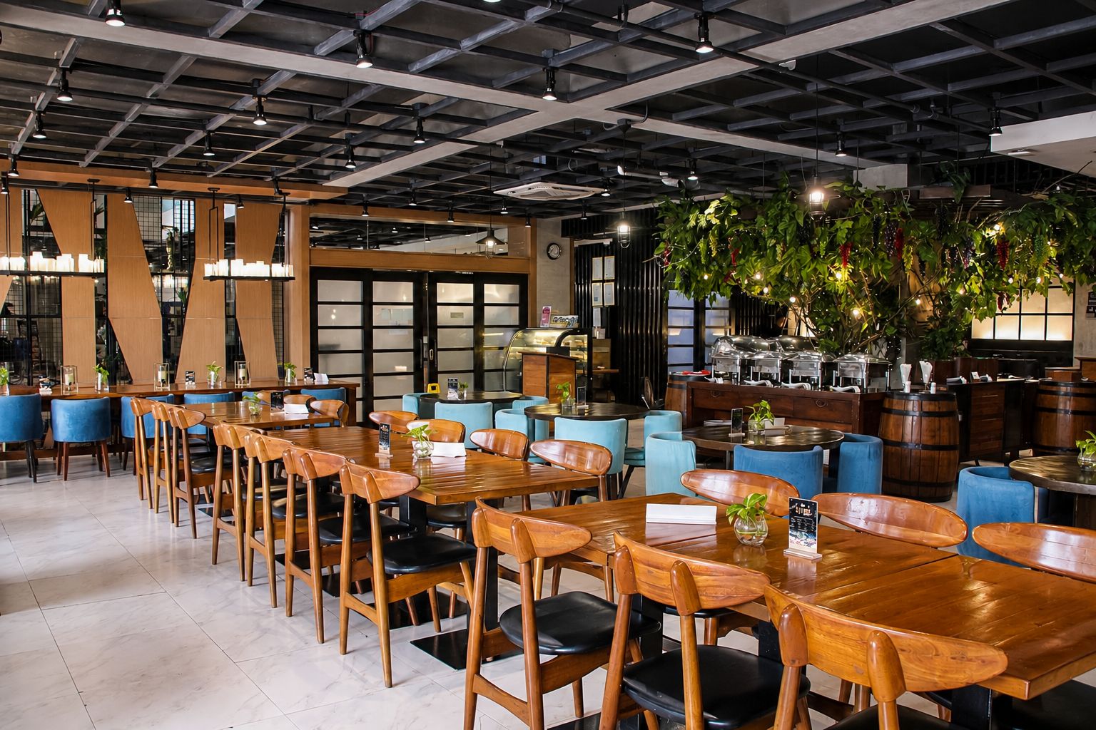 A restaurant with wooden tables and chairs, a bar area with barrels, and a ceiling with exposed beams.