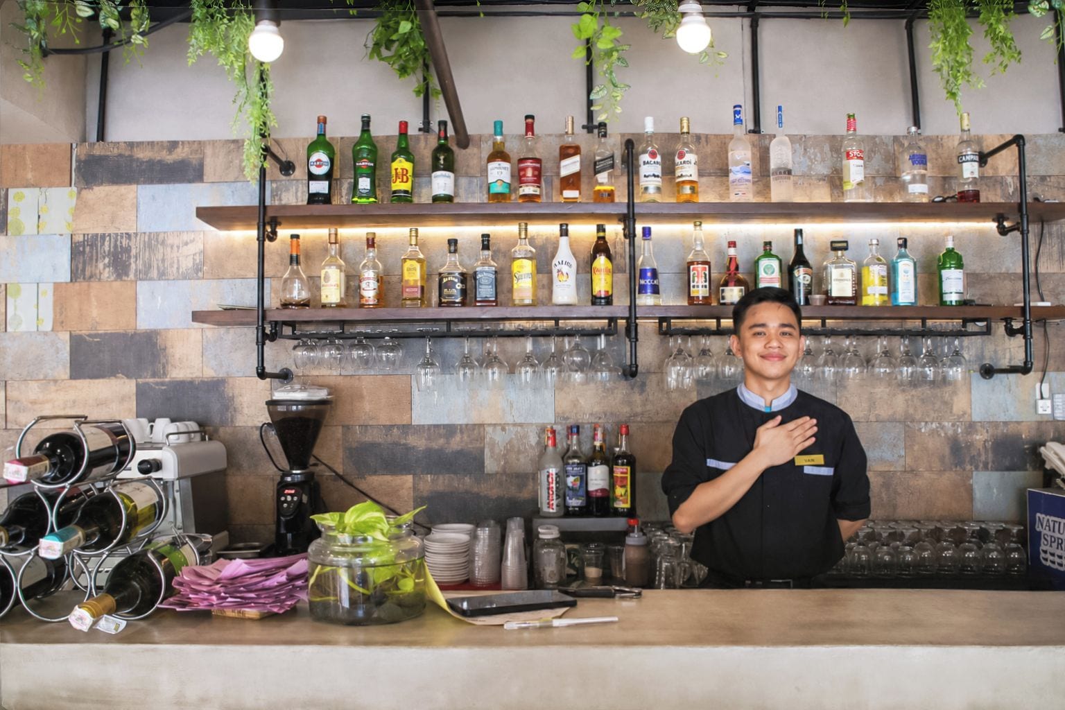 A bar area with shelves of liquor bottles, a coffee machine, and a wine cooler.