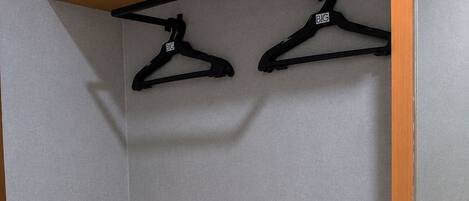 A closet with wooden shelves and two black hangers.