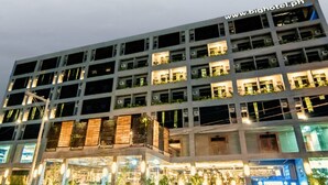 A multi-story hotel with illuminated windows and balconies, a visible website address, and a well-lit entrance area. - Big Hotel (Mandaue)