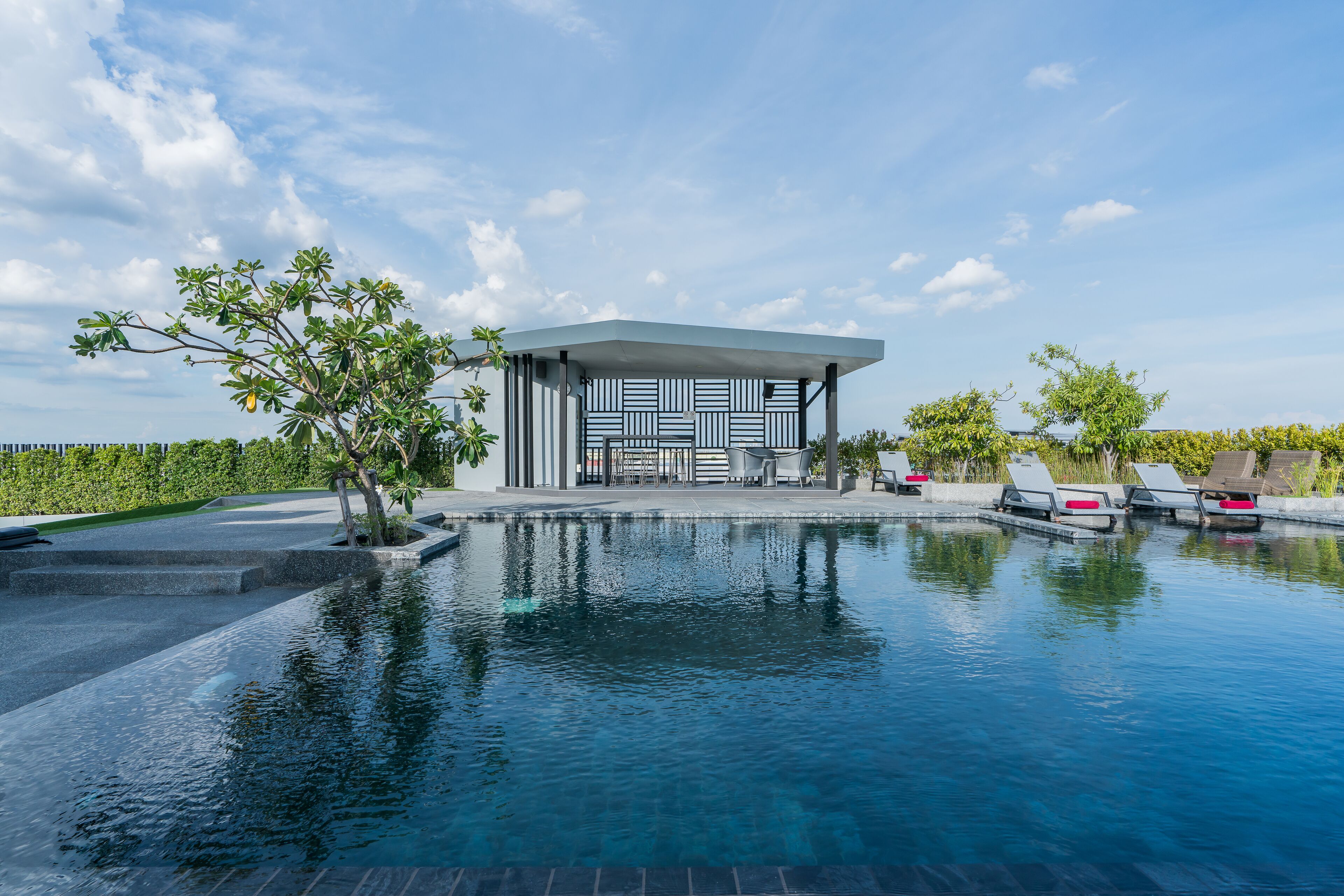 A modern pool area with a geometric pool cover, lounge chairs, and a pavilion with a patterned facade.