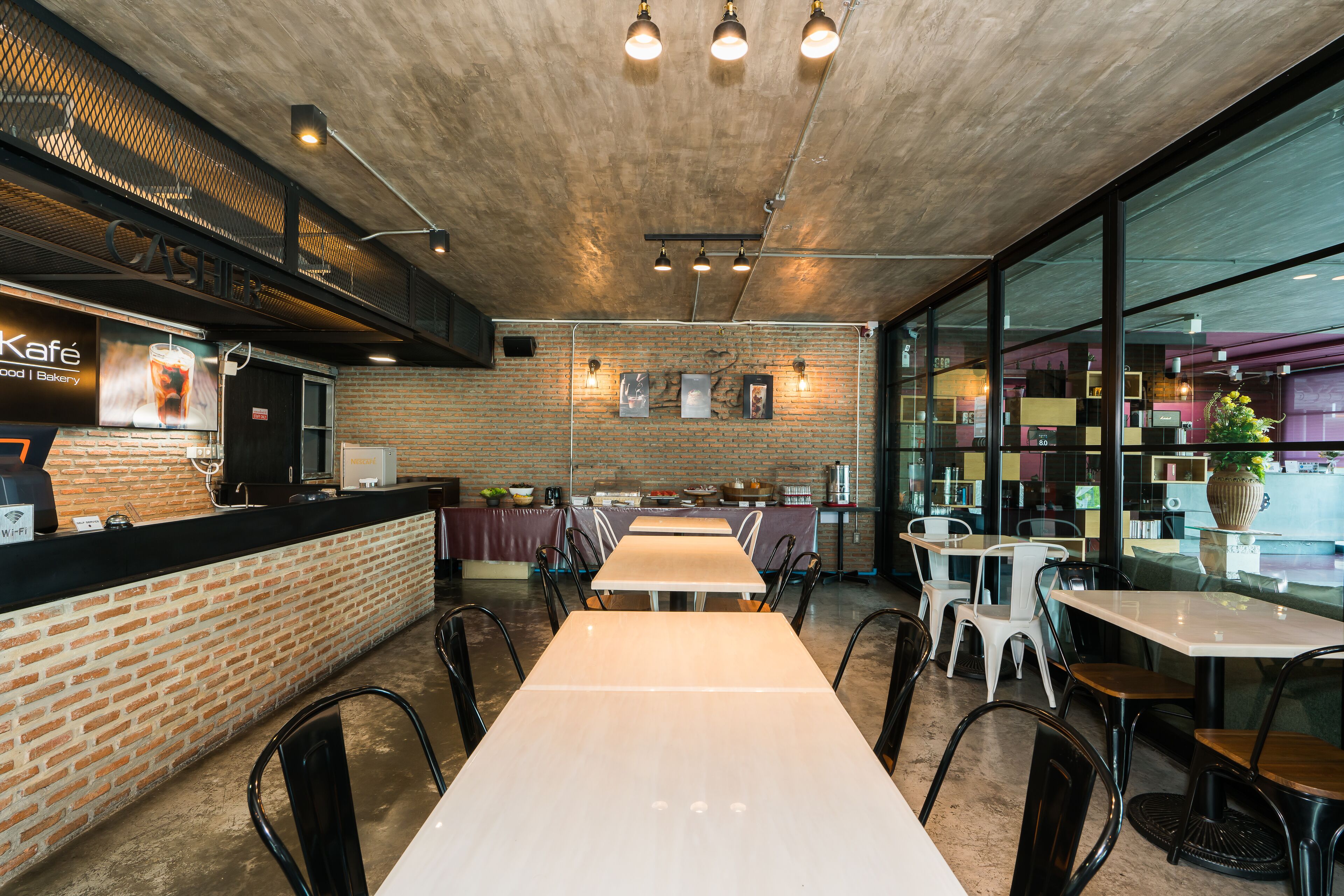 A cafe with brick walls, wooden tables, and black chairs.
