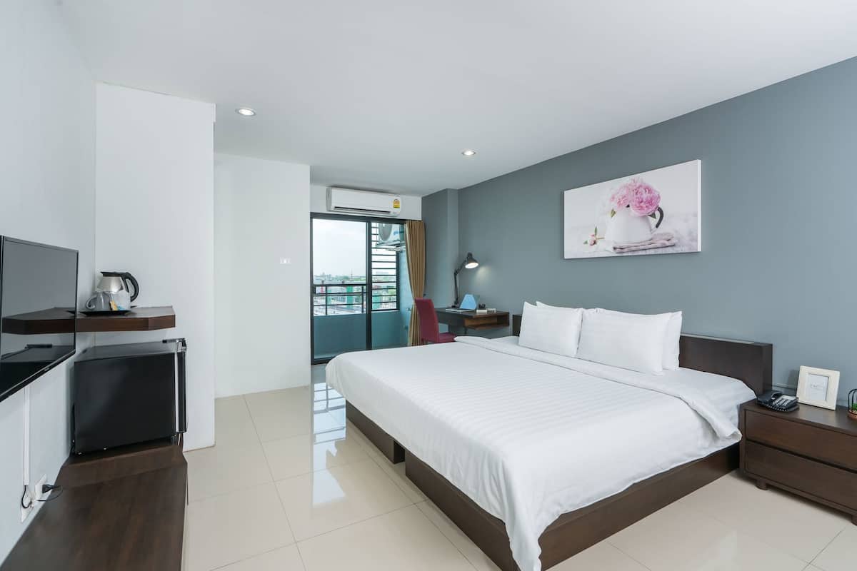 Quarto de hotel moderno com cama, mesa de cabeceira, televisão e vista da cidade.