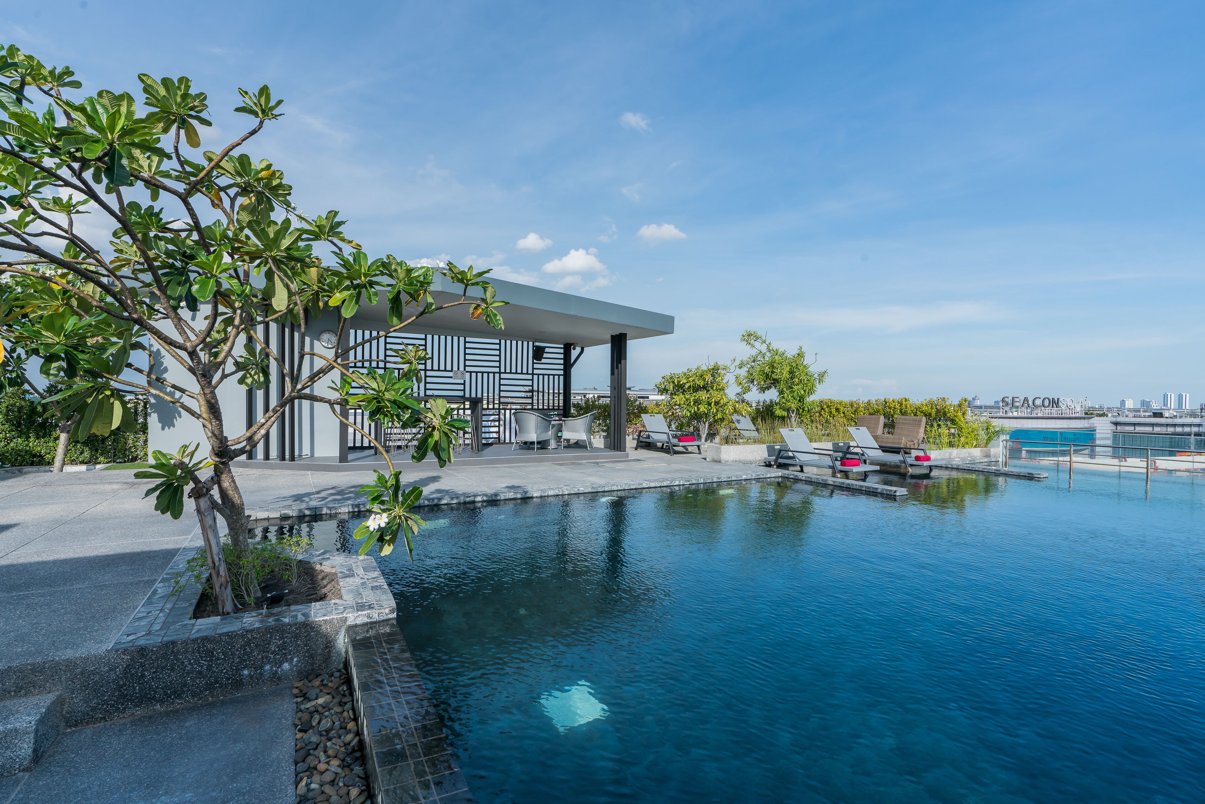 Un espace piscine moderne, doté de chaises longues et d’un bâtiment à la façade géométrique.