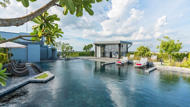 Un espace piscine moderne avec une eau claire, des chaises longues et un petit bâtiment.