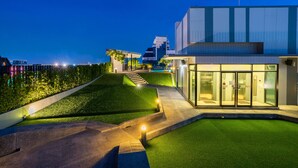 Un bâtiment moderne avec une entrée en verre, une pelouse bien entretenue et un escalier menant à un niveau supérieur.