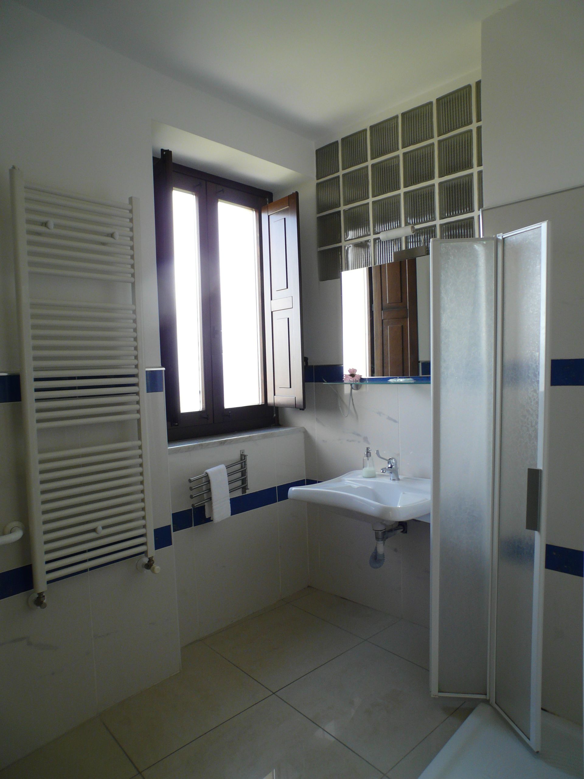 Un baño con ventana, lavabo, espejo y ducha.