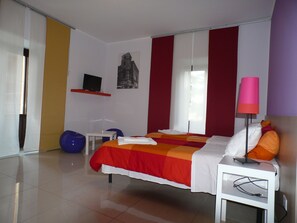 A modern bedroom with a bed, a bedside table, a lamp, a chair, and a television on a shelf. - C.C.Ly Rooms & Hostel Enna (Enna)