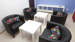 Um quarto com duas poltronas pretas, uma mesa branca e uma parede azul.