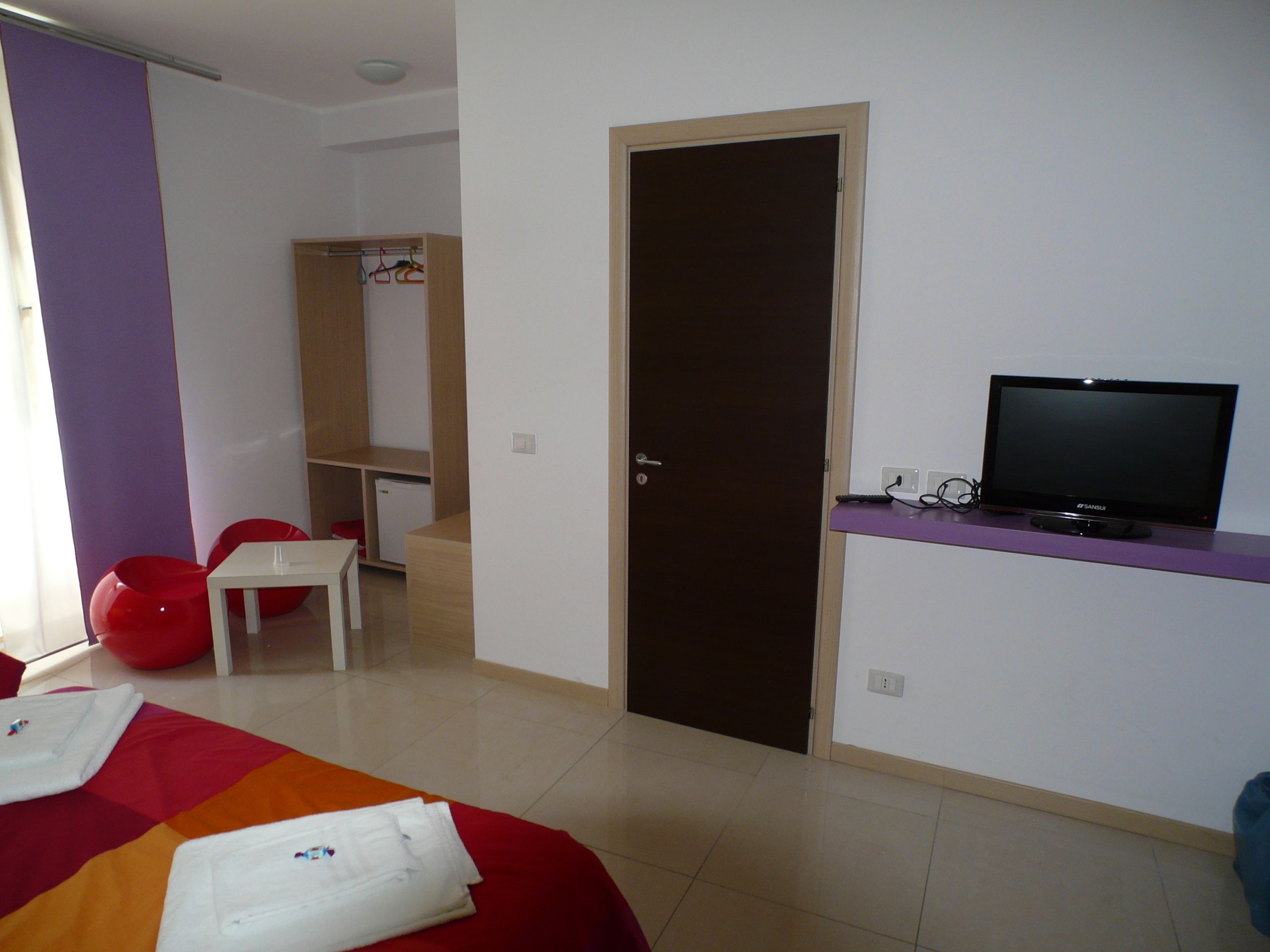 A hotel room with a bed, a TV, a desk, and a wardrobe.