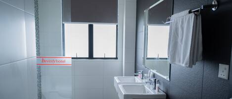 Un baño con ventana, lavabo y espejo.