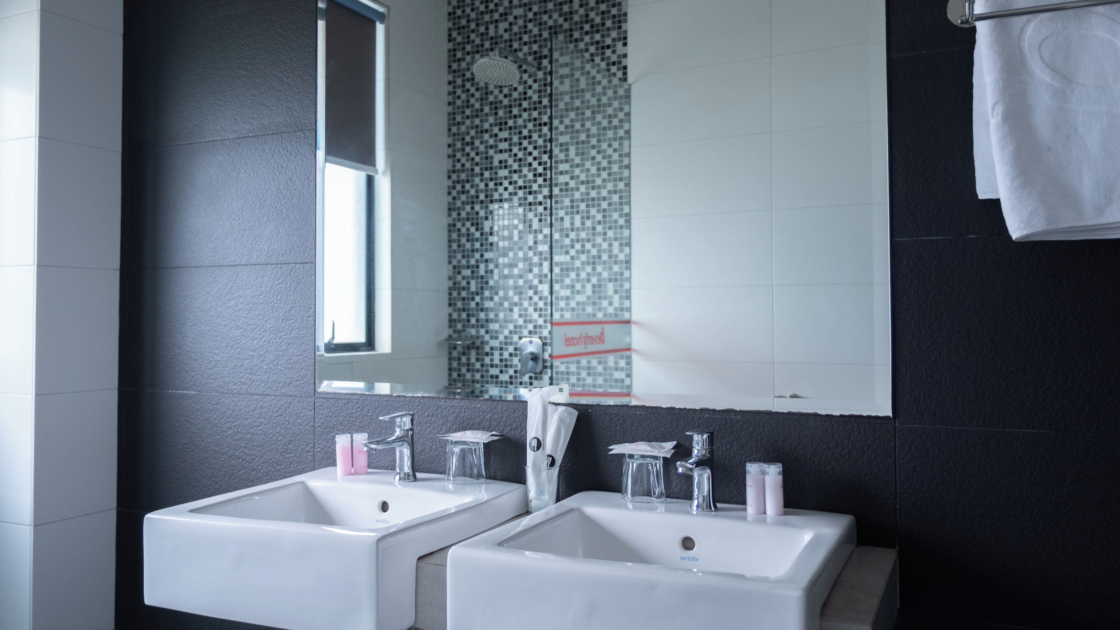 A modern bathroom with two sinks, a mirror, and a shower area.