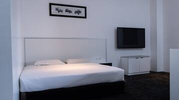 A hotel room with a bed, a television mounted on the wall, and a small cabinet.