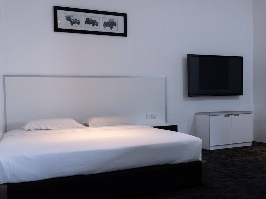 A hotel room with a bed, a television mounted on the wall, and a small cabinet.
