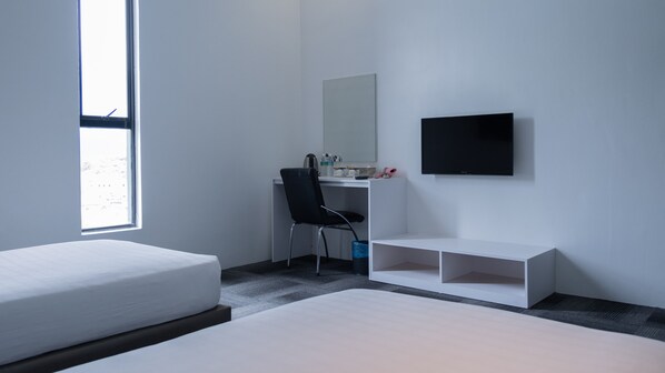 A modern hotel room with a bed, a desk with a chair, a TV, and a window.