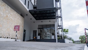 A modern building with a stone facade, a ramp leading to the entrance, and a staircase with a metal railing. - Beverly Hotel (Taiping)