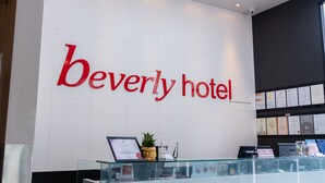 A reception desk at the Beverly hotel with a large sign above it. - Beverly Hotel (Taiping)