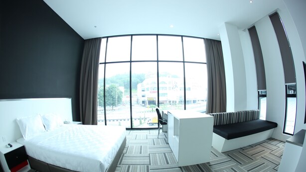 A modern hotel room with a large bed, a desk, and a bench by the window. - Beverly Hotel (Taiping)