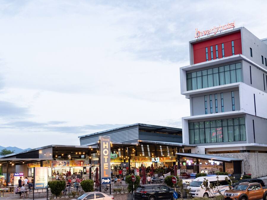 A hotel with multiple floors, a prominent sign, and a bustling street scene with outdoor seating.