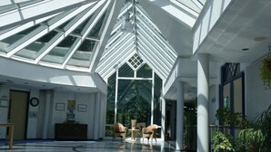 A spacious atrium with a glass ceiling, allowing natural light to fill the area. - Emsland Hotel Saller See (Freren)