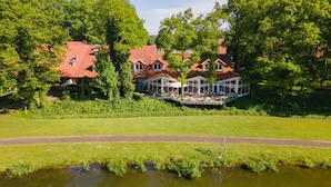 A lakeside property with a covered patio area, a swimming pool, and a well-maintained lawn. - Emsland Hotel Saller See (Freren)