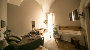 Ein Schlafzimmer mit Bett, Schreibtisch, Stuhl und einer großen Badewanne.